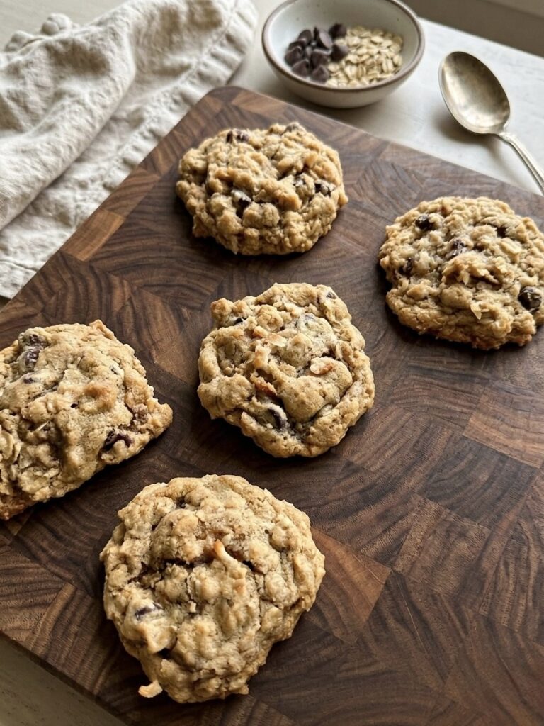 Soft and chewy cowboy cookies with oats, toasted coconut, and chocolate chips on a baking sheet.